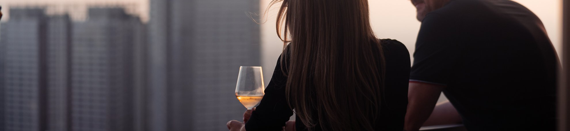 couples drinking wine on the balcony with dtla skyline