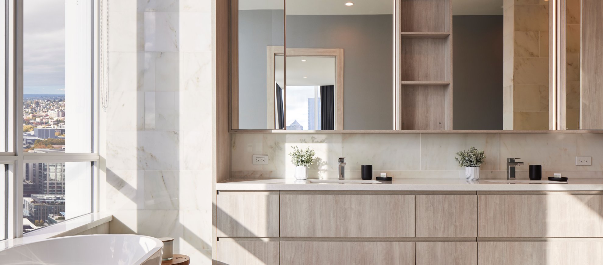 luxury bathroom at level seattle south lake union features tall windows, double vanity, two sinks, large mirror and marble walls and flooring with space needle city view at the penthouse.jpg