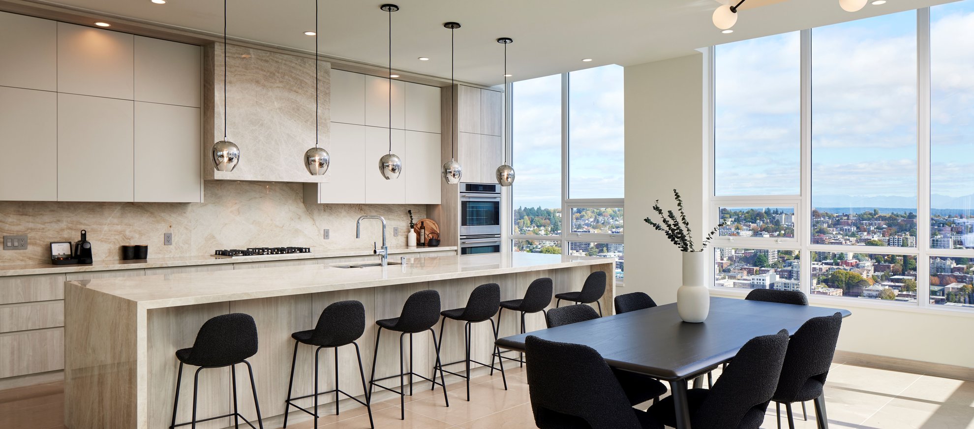 modern kitchen with marble counter island and black dining table with high ceilings and large window at level seattle.jpg